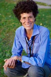 Andrea Constand crouching down in grass with elbow on knee, blue shirt — photo credit Roger Cullman
